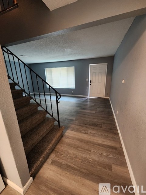 A staircase with a carpeted runner and metal railing leads to a bedroom with a window and a door.