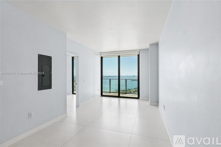 A spacious room with a view of the ocean through a sliding glass door.