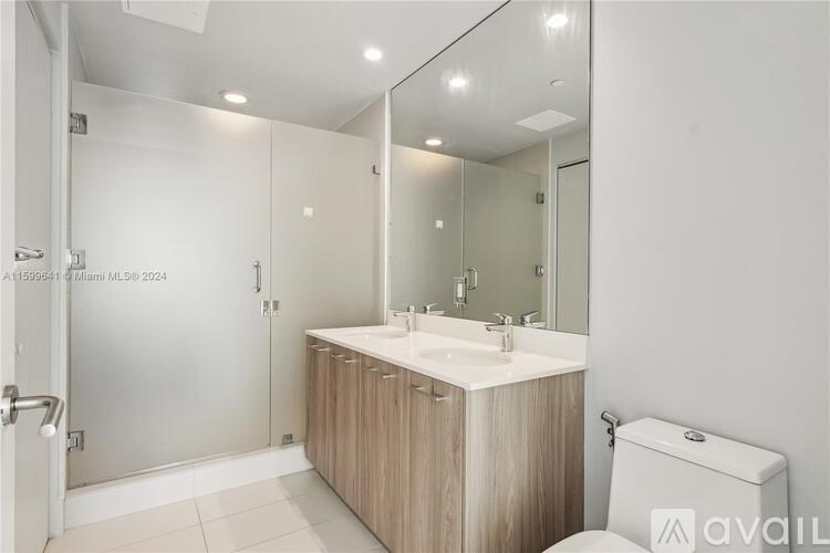 A bathroom with a sink, mirror, toilet and shower.