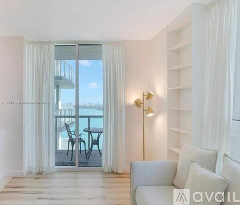 A living room with a grey sofa and a table with chairs outside the window.
