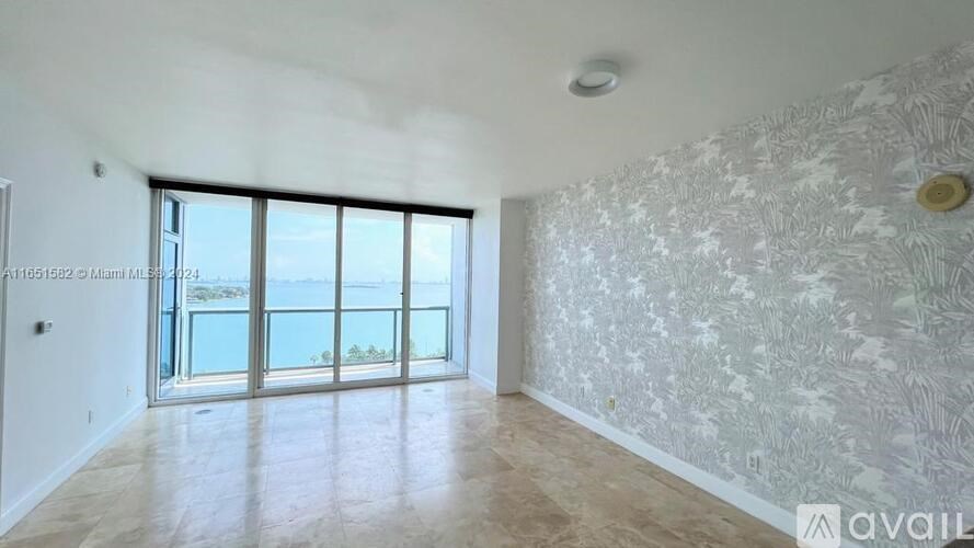 A room with a large window and a wallpapered wall.