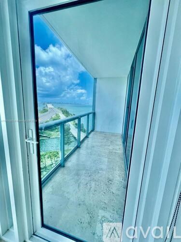 A balcony with a glass door leading to a view of the sky and a distant building.