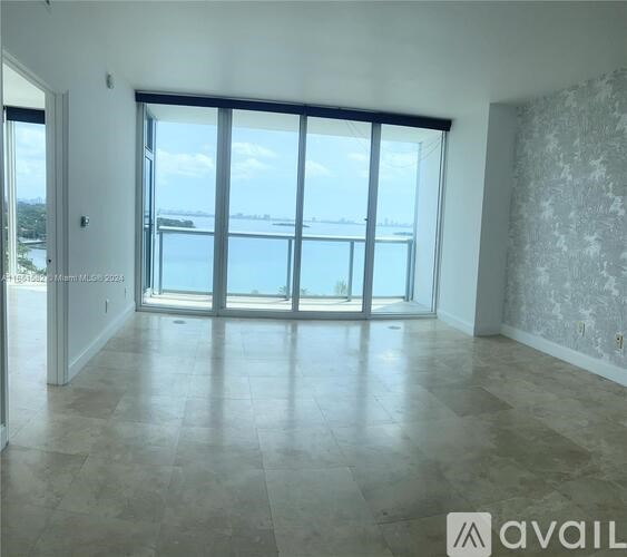 A spacious room with large windows overlooking a body of water.