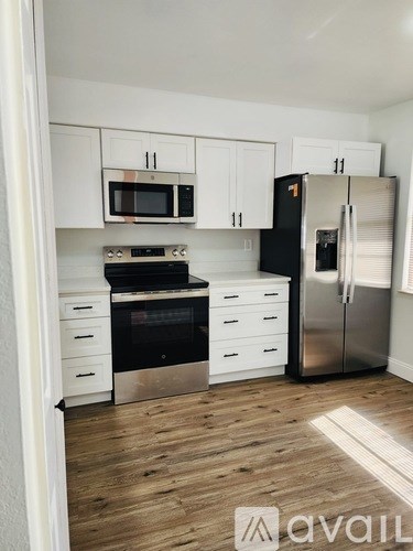 A kitchen with white cabinets and a black fridge.