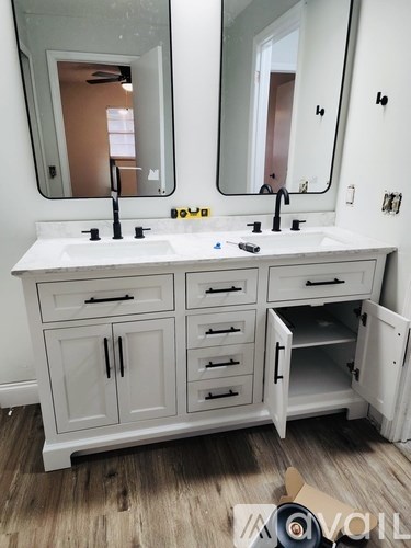 A bathroom vanity with a white countertop and a mirror above it.