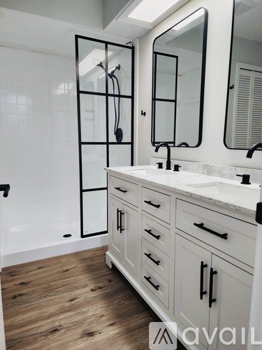 A bathroom with a white vanity and a walk-in shower.