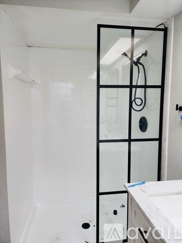 A white bathroom with a glass shower door and a white sink.