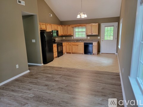 A kitchen with wooden cabinets and a black refrigerator.