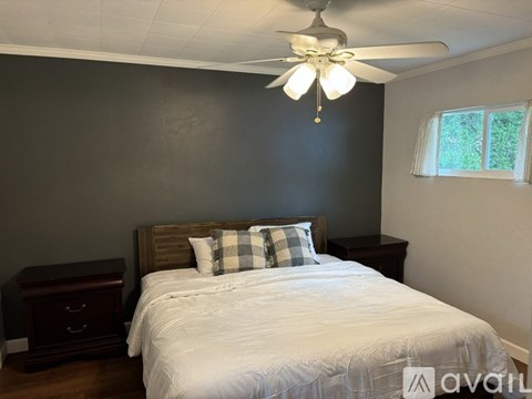 A bedroom with a bed, nightstand, and window.