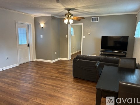A living room with a black leather couch and a television.