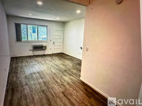 A spacious room with white tiled flooring and a window with blinds.
