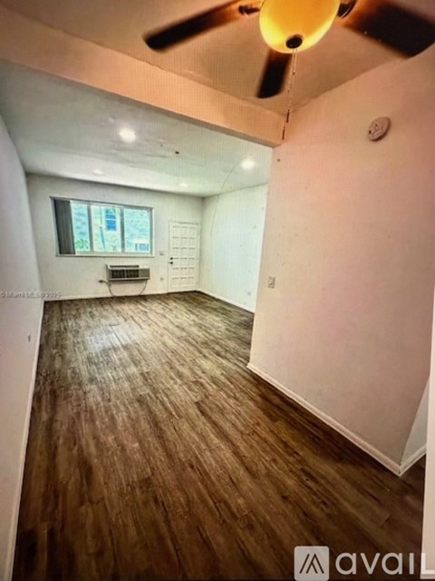 A white tiled hallway with a door on the left.
