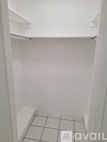 A white closet with a tiled floor.