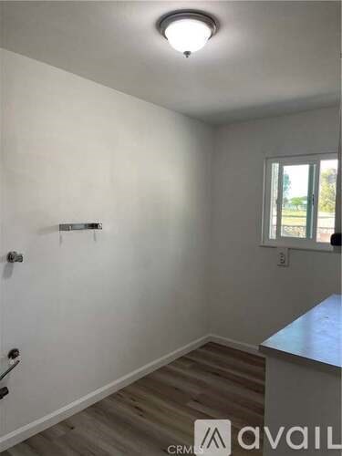 A room with a white door and a window with a view of trees outside.