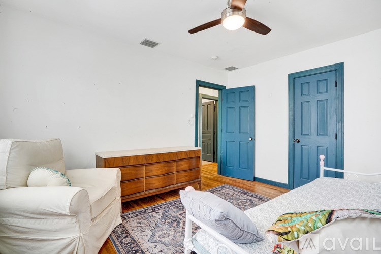 A bedroom with a bed, a chair, and a dresser with two doors.