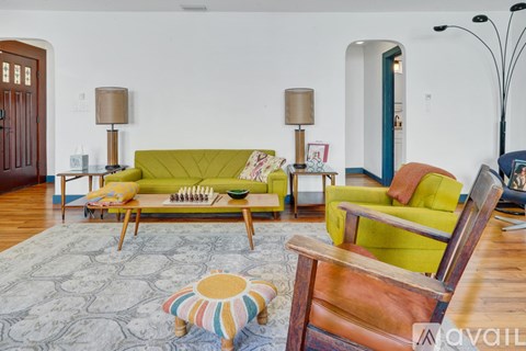 A living room with a green couch and a wooden chair.