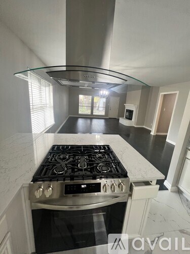 A modern kitchen with a stove top oven and a glass hood.