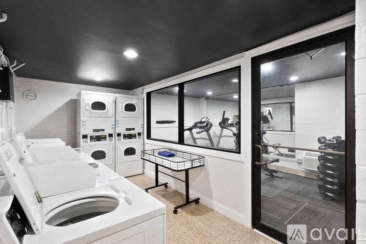 A modern laundry room with a washer and dryer, a folding table, and a view into the living room.
