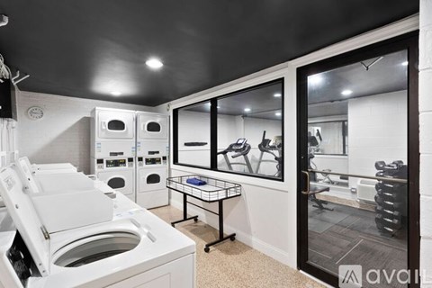 A modern laundry room with a washer and dryer, a folding table, and a view into the living room.