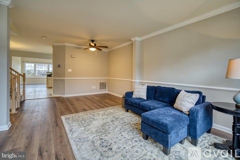 A living room with a blue couch and a rug.