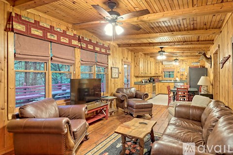 A living room with brown leather furniture and a ceiling fan.