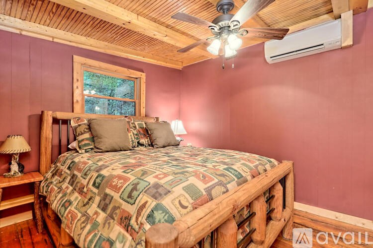A bedroom with a bed, wooden headboard, and a ceiling fan.