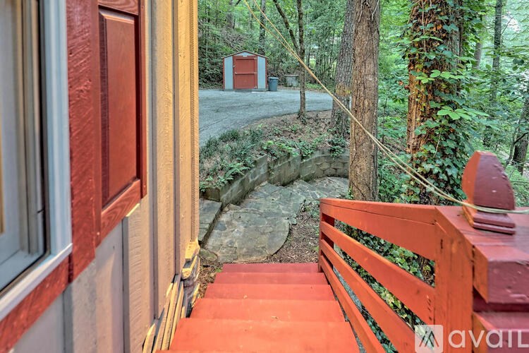 A wooden bench is on a porch with a view of a forest.