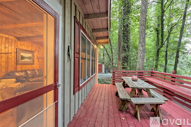 A wooden deck with a picnic table and benches overlooking a forest.