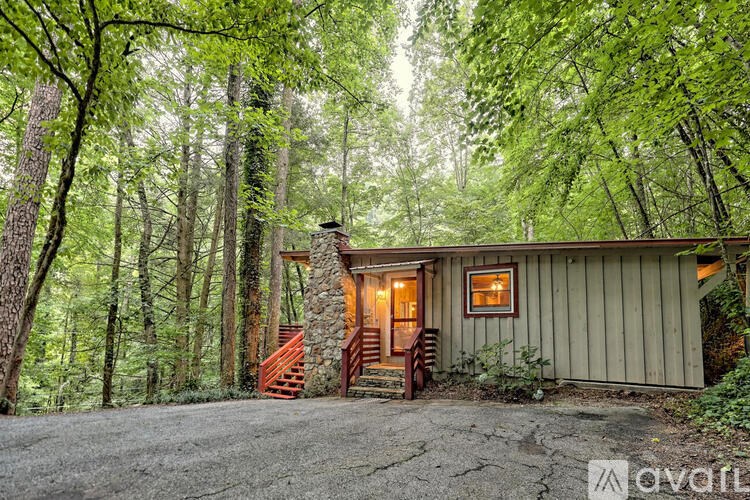 A house with a stone chimney is surrounded by trees.