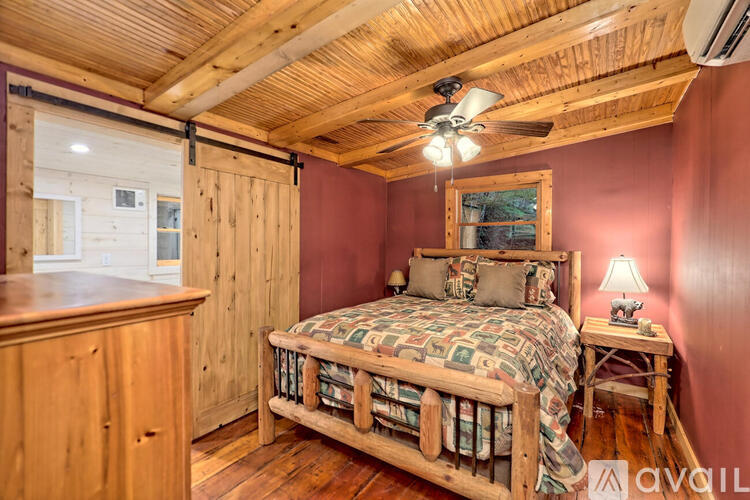 A bedroom with a bed, wooden dresser, and a ceiling fan.