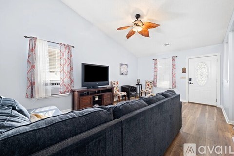 A living room with a grey couch and a television on a wooden stand.