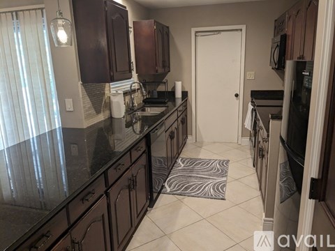 A kitchen with dark brown cabinets and black countertops.
