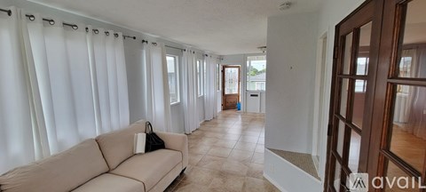 A living room with a couch and a window with curtains.