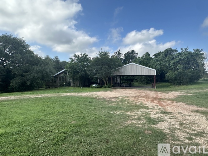A barn sits in a field with trees in the background.
