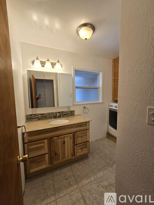 A bathroom with a sink, mirror, and wooden cabinets.