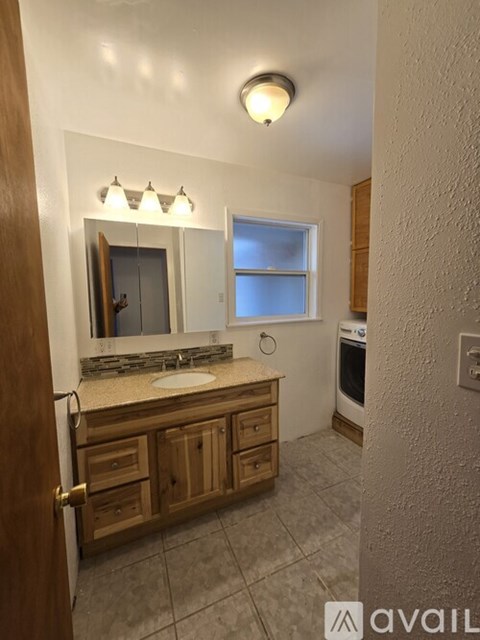 A bathroom with a sink, mirror, and wooden cabinets.