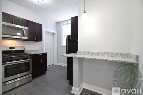 A kitchen with dark wood cabinets and a stainless steel oven.