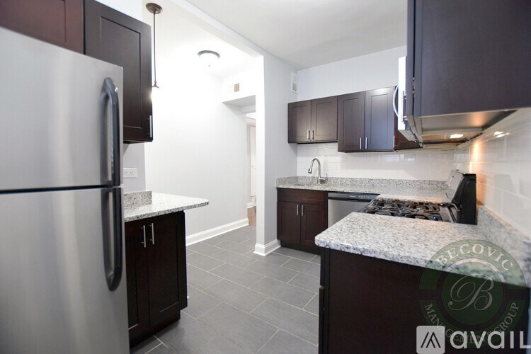 A kitchen with a refrigerator, cabinets, and a counter.
