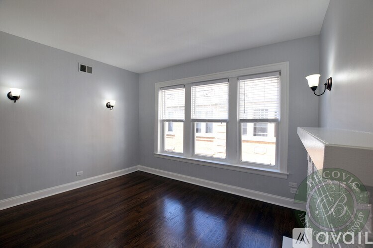 A room with wooden floors and a window with blinds.