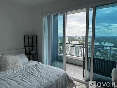 A bedroom with a large bed and a view of the city through the window.