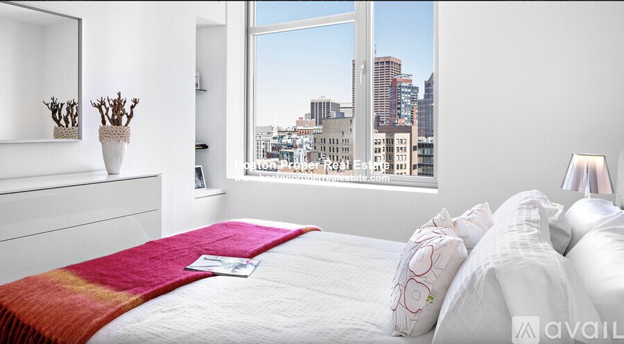 A bedroom with a large window overlooking a cityscape.