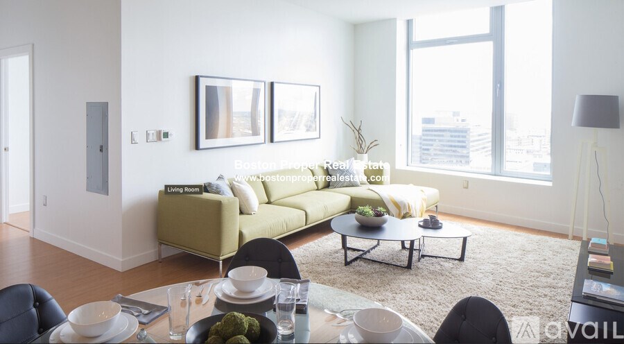 A living room with a sofa, coffee table, and a dining table set for two.