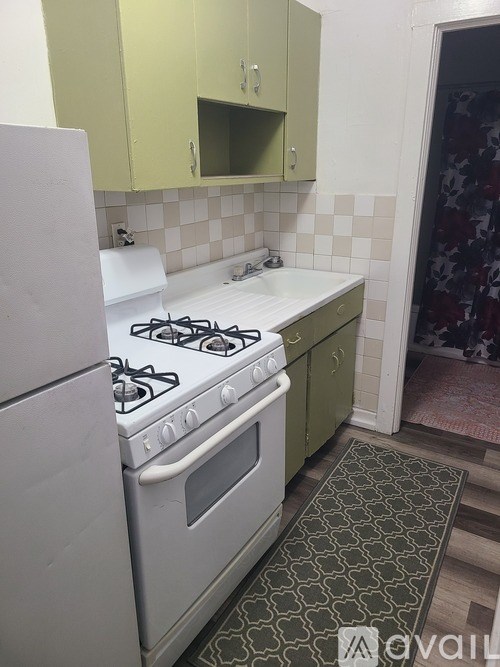 A kitchen with a white stove and green cabinets.