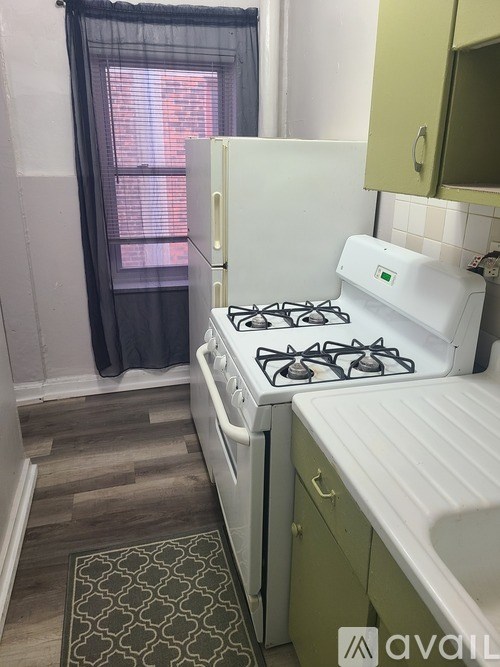 A small kitchen with a white gas stove and green cabinets.