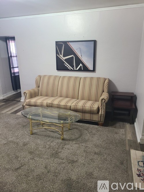 A living room with a striped couch and a glass coffee table.