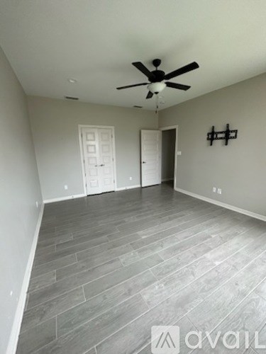 A room with a ceiling fan and grey flooring.