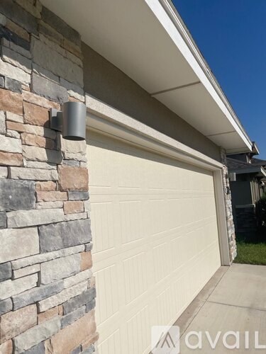 A garage door is closed and attached to a stone wall.