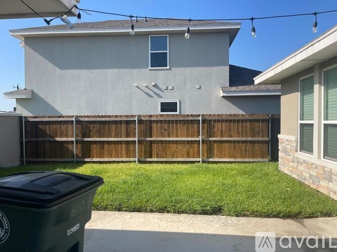A house with a grey exterior and a green trash bin in front.