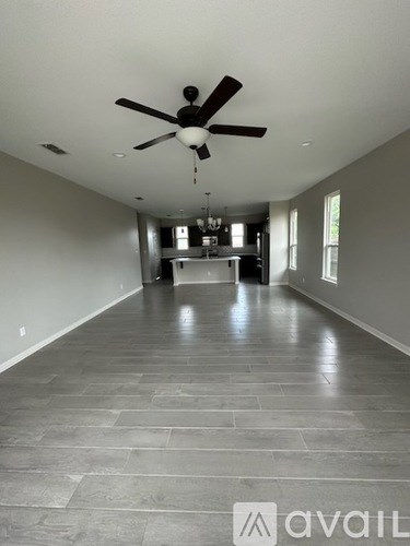 A spacious room with a ceiling fan and a kitchen in the background.
