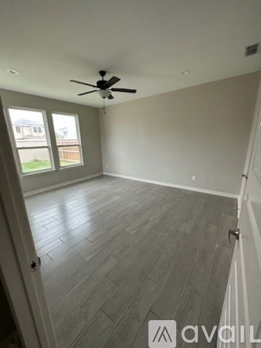 A room with a ceiling fan and wood flooring.